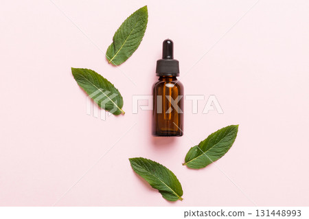 Natural Mint Essential Oil in a Glass Bottle. organic cosmetics with herbal extracts of mint on colored background 131448993
