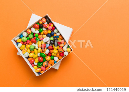 Set of different sweet candy in a paper box with a satin ribbon on a colored background. Holiday concept 131449039