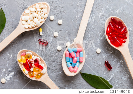 Vitamin capsules in a spoon on a colored background. Pills served as a healthy meal. Red soft gel vitamin supplement capsules on spoon Vitamin capsules in a spoon on a colored background. Pills served as a healthy meal. Red soft gel vitamin supplement capsules on spoon 131449048