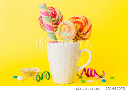 Colorful candies in cup on table on light background background. Large swirled lollipops. Creative concept of a jar full of delicious sweets from the candy store 131449053