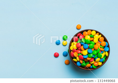 Multicolored candies in a bowl on a colored background. birthday and holiday concept. Top view with copy space Multicolored candies in a bowl on a colored background. birthday and holiday concept. Top view with copy space 131449068