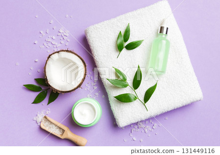 Coconut with jars of coconut oil and cosmetic cream on colored background. Top view. Free space for your text. Natural spa coconut cosmetics and organic treatment concept Coconut Spa composition 131449116