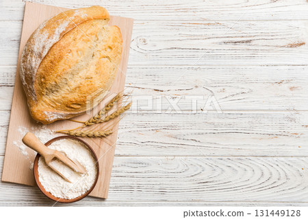 Freshly baked bread on cutting board against white wooden background. top view bread with copy space 131449128