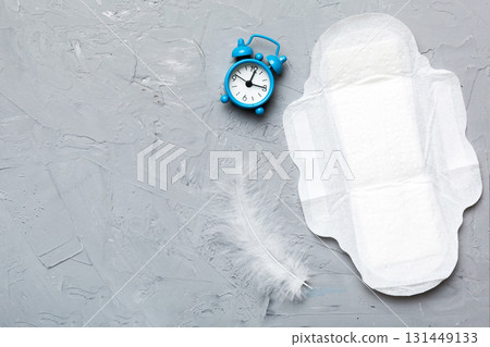 Ringing alarm clock with sanitary female tampons and menstrual sanitary pads. Medical concept of woman critical days and menstruation. Female daily hygiene. Copy space Ringing alarm clock with sanitary female tampons and menstrual sanitary pads. Medical concept of woman critical days and menstruation. Female daily hygiene. Copy space 131449133