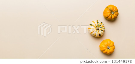 Autumn composition of little orange pumpkins on colored table background. Fall, Halloween and Thanksgiving concept. Autumn flat lay photography. Top view vith copy space Autumn composition of little orange pumpkins on colored table background. Fall, Halloween and Thanksgiving concept. Autumn flat lay photography. Top view vith copy space 131449178