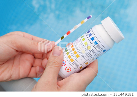 Analysis of the PH and chlorine of the water in a swimming pool in Summer. Check quality of water with test strip, comparing results Analysis of the PH and chlorine of the water in a swimming pool in Summer. Check quality of water with test strip, comparing results 131449191