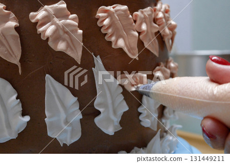 Confectioner woman is pouring cream on sponge cake using pastry bag, closeup view. Pastry chef is cooking homemade cake. cooking, baking and cooking, home cooking 131449211