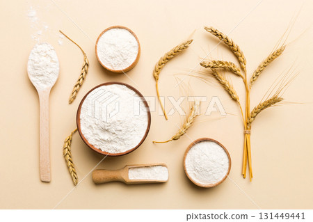 Flat lay of Wheat flour in wooden bowl with wheat spikelets on colored background. world wheat crisis 131449441