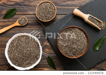 Chia seeds in bowl and spoon on colored background. Healthy Salvia hispanica in small bowl. Healthy superfood Chia seeds in bowl and spoon on colored background. Healthy Salvia hispanica in small bowl. Healthy superfood 131449478