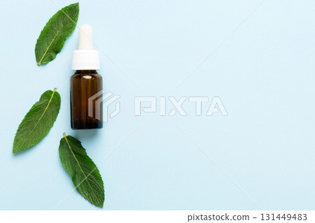Natural Mint Essential Oil in a Glass Bottle. organic cosmetics with herbal extracts of mint on colored background Natural Mint Essential Oil in a Glass Bottle. organic cosmetics with herbal extracts of mint on colored background 131449483