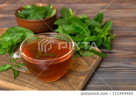 Cup of mint tea on table background. Green tea with fresh mint top view with copy space Cup of mint tea on table background. Green tea with fresh mint top view with copy space 131449489