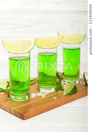 Sweet refreshing mint liqueur, with ice and mint leaves on table background, Shots with lime slice and mint flat lay 131449504