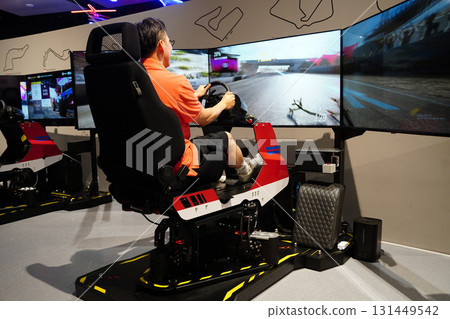 Person Playing a Racing Game on a Simulator with Triple Monitors 131449542
