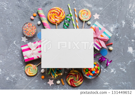 Flat lay holiday composition. Paper blank, lollipop, birthday decorations on Colored background. Top view, copy space for text 131449652