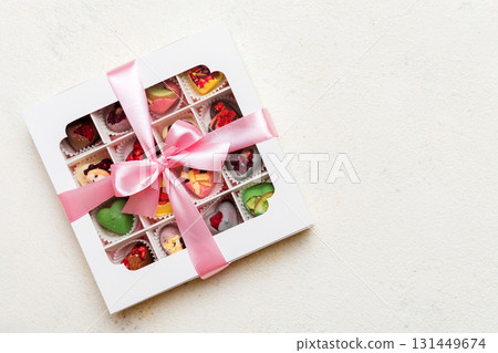 Box with sweet chocolate candies on color background, Various candy sweets. Valentines day gift box. Top view flat lay with copy space Box with sweet chocolate candies on color background, Various candy sweets. Valentines day gift box. Top view flat lay with copy space 131449674