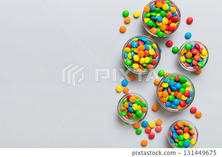 different colored round candy in bowl and jars. Top view of large variety sweets and candies with copy space different colored round candy in bowl and jars. Top view of large variety sweets and candies with copy space 131449675