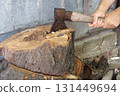 Cutting wood with a large sharp ax, Man Chops firewood, Chopping of wood on a wooden log in summer at the home 131449694