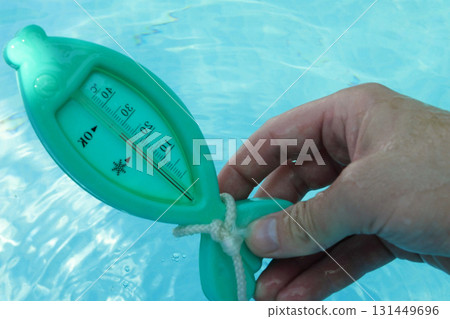 a man hand checks the temperature with a thermometer on a sunny day 131449696