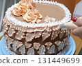 Confectioner woman is pouring cream on sponge cake using pastry bag, closeup view. Pastry chef is cooking homemade cake. cooking, baking and cooking, home cooking 131449699