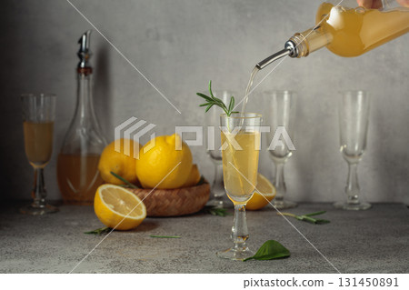 Italian liqueur Limoncello with fresh lemons and rosemary branches on a gray stone table. 131450891