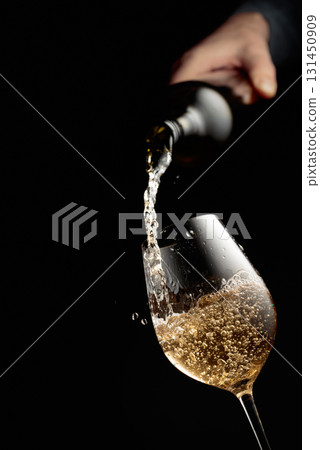 Pouring white wine in a glass goblet. Pouring white wine in a glass goblet. 131450909