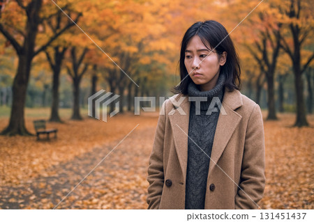 A woman standing lonely in an autumn park A woman standing lonely in an autumn park 131451437