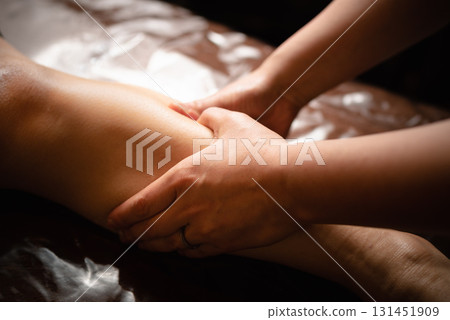 在燈光昏暗的美容院裡用雙手按摩小腿區域 131451909