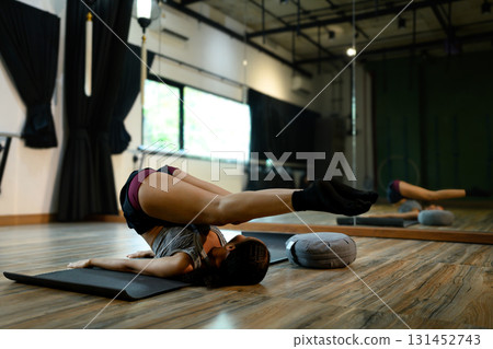 Athletic female performing plow pose exercise on wooden floor, healthy lifestyle and wellness concept Athletic female performing plow pose exercise on wooden floor, healthy lifestyle and wellness concept 131452743