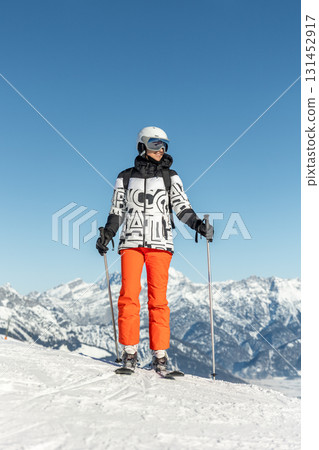 Young adult confident woman skier portrait at winter alpine skiing resort. Female sporty person with backpack mountain Alps snow slope outdoors cold snowy sunny backlit light day Young adult confident woman skier portrait at winter alpine skiing resort. Female sporty person with backpack mountain Alps snow slope outdoors cold snowy sunny backlit light day 131452917