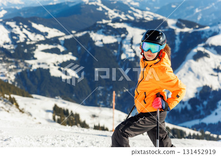 Active confident adorable teenager caucasian kid girl portrait with ski in helmet, goggles and bright suit enjoy winter extreme sport activities. Little child skiing luxury alpine resort in mountains Active confident adorable teenager caucasian kid girl portrait with ski in helmet, goggles and bright suit enjoy winter extreme sport activities. Little child skiing luxury alpine resort in mountains 131452919