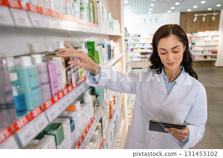 Healthcare professional woman reviewing stock in pharmacy 131453102