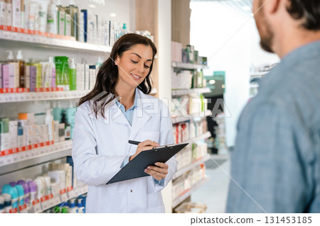 Brunette woman pharmacist making notes while consulting client 131453185