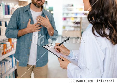 Dark-haired woman pharmacist recording information during client consultation 131453231