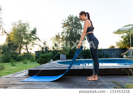 Slim woman in sportswear putting yoga mat on the ground 131453258