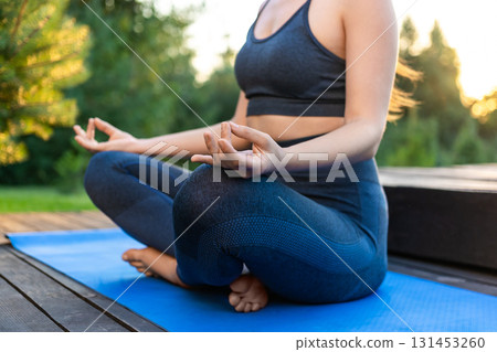 Young woman sitting in lotus pose and meditating 131453260