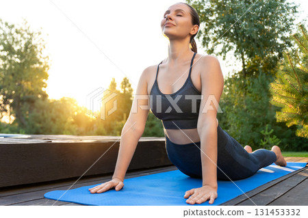 Young woman on a yoga mat in upward facing dog pose 131453332