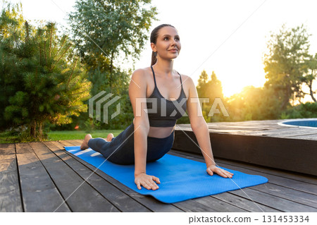 Young woman on a yoga mat in upward facing dog pose 131453334