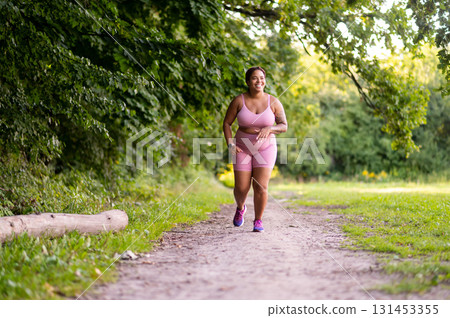 Plus size young woman running in the forest and looking enjoyed 131453355
