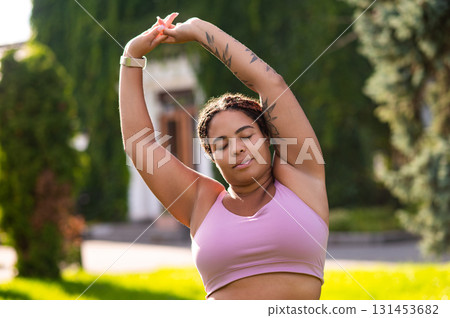 Woman in pink sportswear doing stretching and looking relaxed Woman in pink sportswear doing stretching and looking relaxed 131453682