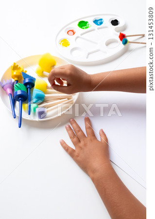 Child engaged in creative painting with sponge brushes and vibrant colors 131453809