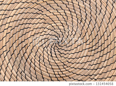 Seagrass place mat, clockwise wound in the shape of a spiral, and sewn with black thread. Natural and organic underlay, made of sedge, a natural Asian seagrass. Background. Close-up, from above. Photo 131454058
