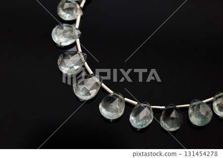 Moss aquamarine faceted briolette beads against a black background 131454278