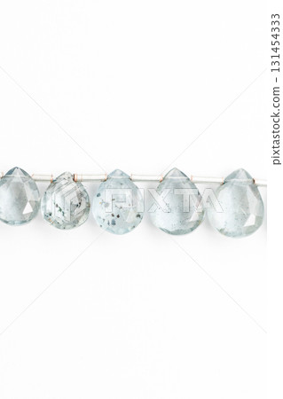 Moss aquamarine faceted drop cuts arranged on a white background 131454333