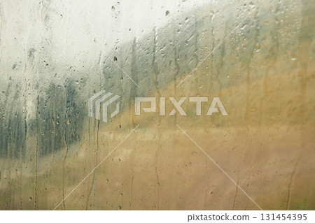 A foggy view from a cable car window, showing blurred mountains and rain droplets on the glass. The landscape appears muted and serene, ideal for a vacation setting. A foggy view from a cable car window, showing blurred mountains and rain droplets on the glass. The landscape appears muted and serene, ideal for a vacation setting. 131454395