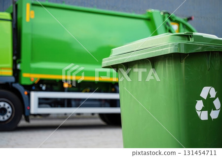 Green Recycling Bin and Garbage Truck in Urban Setting 131454711