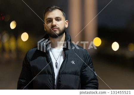 Young man posing in black puffer jacket in urban night 131455521