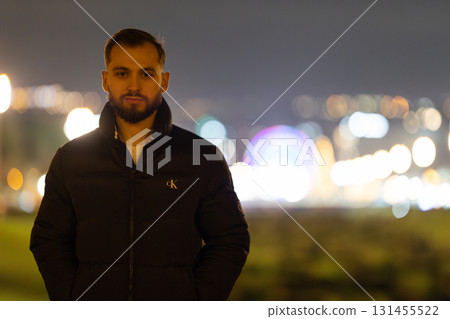 Young adult man standing outdoors at night urban scene Young adult man standing outdoors at night urban scene 131455522