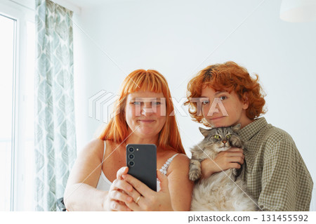 Mom and daughter take selfie with pet cat at home 131455592