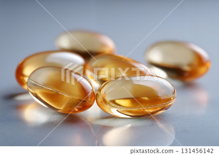 Golden Softgel Capsules of Omega 3 Fish Oil on Gray Background 131456142