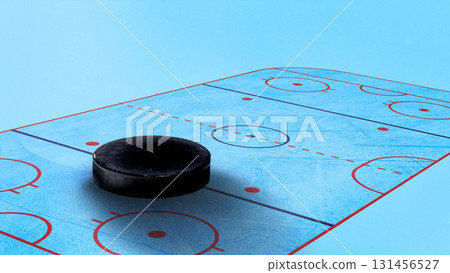 Creative collage. Giant hockey puck on blue ice rink with marked zones Creative collage. Giant hockey puck on blue ice rink with marked zones 131456527
